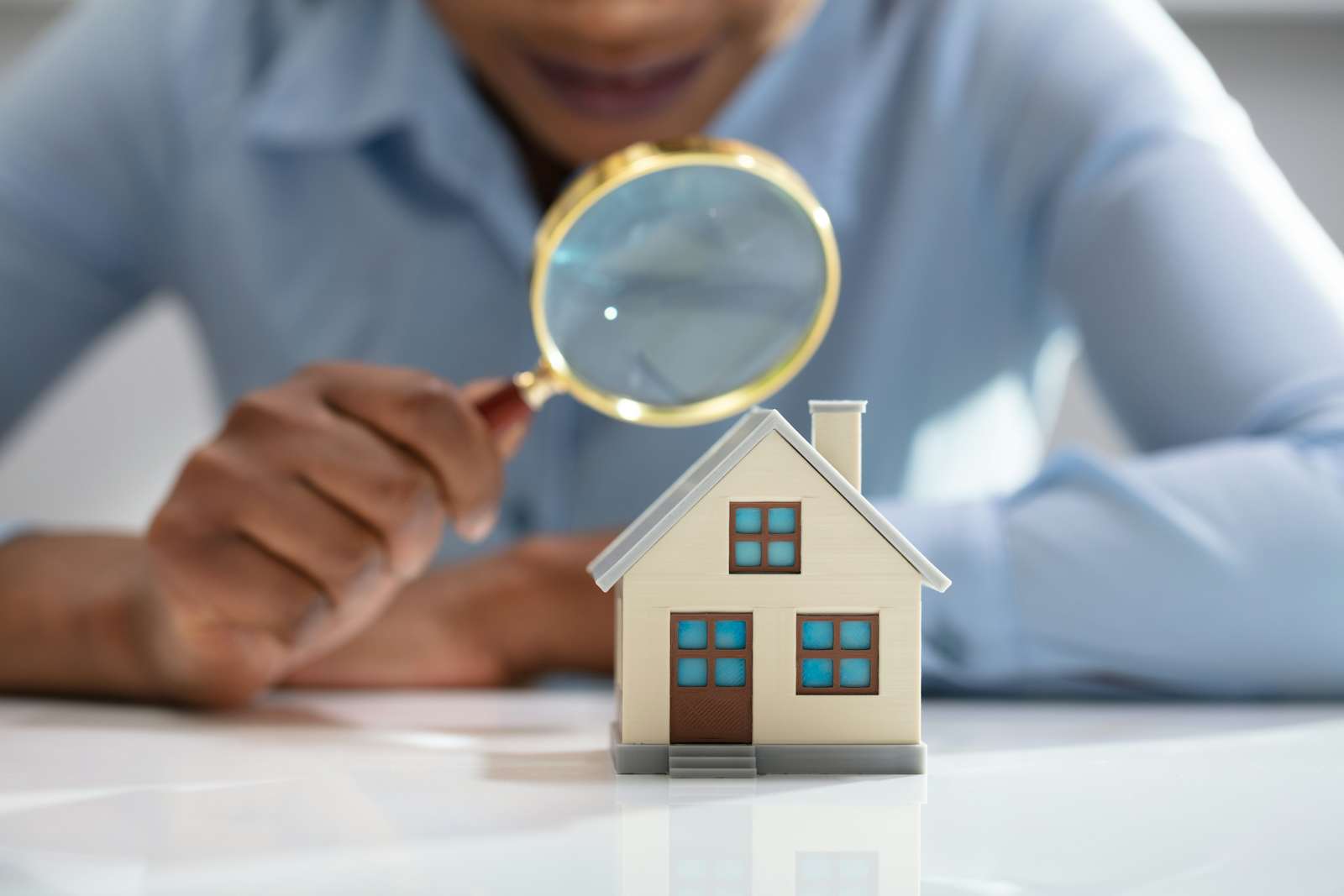 Businesswoman Holding Magnifying Glass Over House